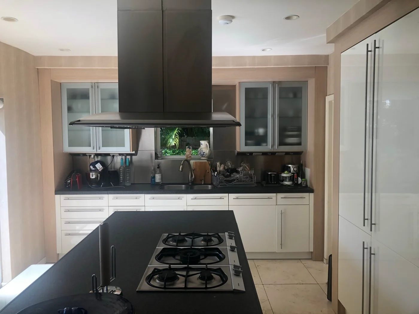 The same Miami kitchen before: white cabinets, black counters and a gas cooktop on the island