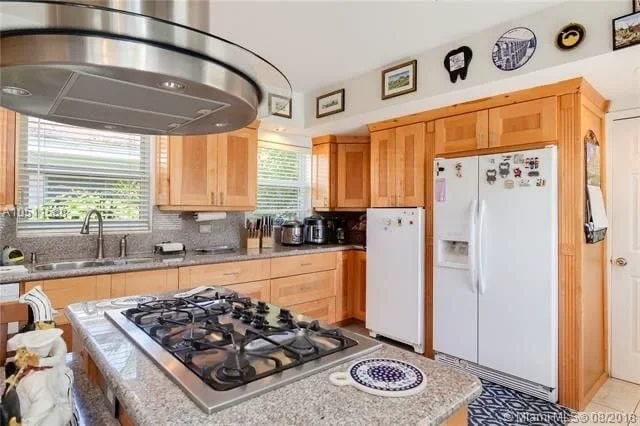 The same kitchen before: oak cabinetry, a round steel hood and a white refrigerator