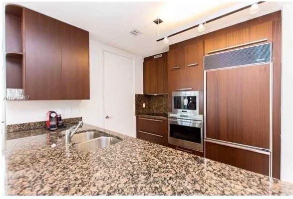Miami kitchen before: cherry cabinets and a speckled granite counter