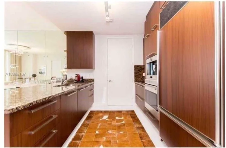 The same galley kitchen before: cherry cabinetry and an orange tile runner